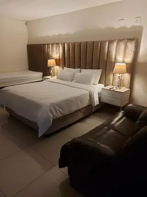 a bedroom with a large bed and a couch at Purple Olive Guest House in Pretoria
