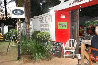 a coffee shop with a table and chairs and a sign at Brooklyn Guesthouses in Pretoria