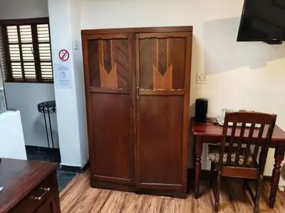 a large wooden cabinet in a room with a table at Brooklyn Guesthouses in Pretoria