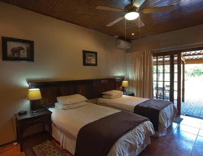 a bedroom with two beds and a ceiling fan at Sunbird Lodge in Phalaborwa