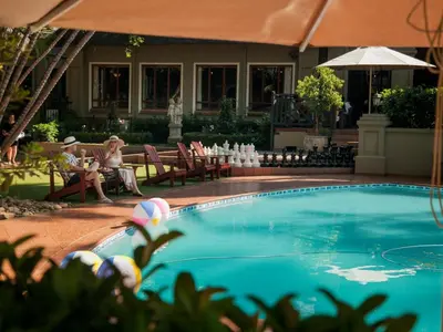 two people sitting in chairs next to a swimming pool at Fairview Hotels,Spa & Golf Resort in Tzaneen