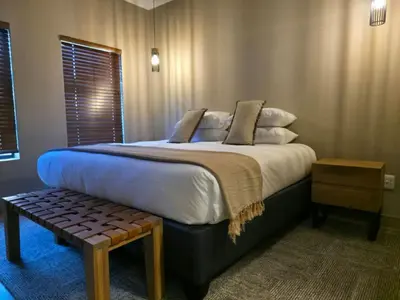 a bedroom with a large bed with a bench next to it at Fairview Hotels,Spa & Golf Resort in Tzaneen