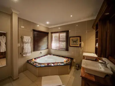 a bathroom with a tub with a lot of rocks around it at Fairview Hotels,Spa & Golf Resort in Tzaneen