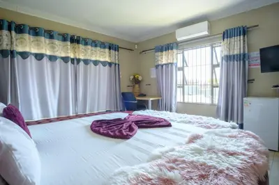 a bedroom with a large white bed with purple blankets at Alimop Bed and Breakfast in Midrand