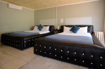 two beds in a room with blue and white pillows at Alimop Bed and Breakfast in Midrand
