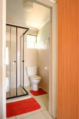 a bathroom with a toilet and a glass shower at Alimop Bed and Breakfast in Midrand