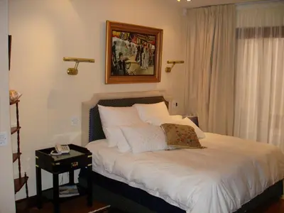 a bedroom with a white bed with a nightstand next to a window at Kosmos Manor Guest House in Hartbeespoort