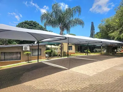 a group of white umbrellas in front of a building at Apricity Inn in Louis Trichardt