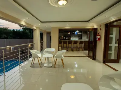 a balcony with white chairs and a bar at Global Village Guest House in Nelspruit