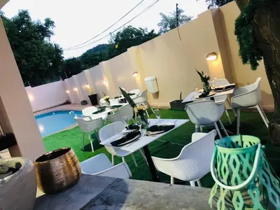 a patio with white tables and chairs next to a pool at Global Village Guest House in Nelspruit