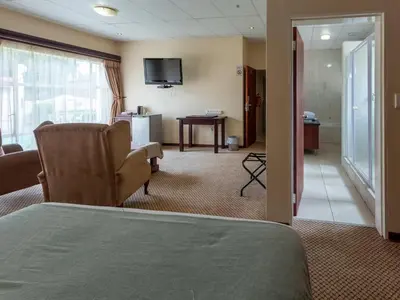 a hotel room with a bed and a living room at Global Village Guest House in Nelspruit