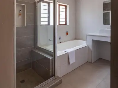 a bathroom with a shower and a tub and a sink at Global Village Guest House in Nelspruit