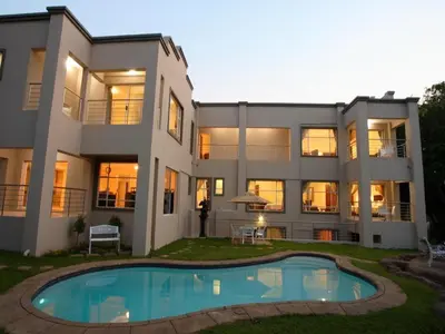 a large house with a pool in front of it at Global Village Guest House in Nelspruit