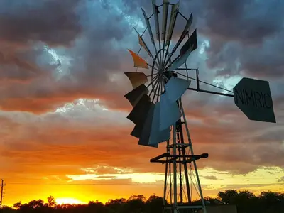 an old fashioned windmill with a sunset in the background at OuKlip Game Lodge in Klipdrift