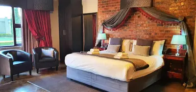 a bedroom with a large bed with a brick wall at Accolades Boutique Venue in Midrand
