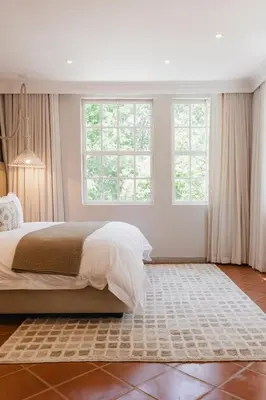 a bedroom with a large bed and two windows at Bly B&B in Pretoria