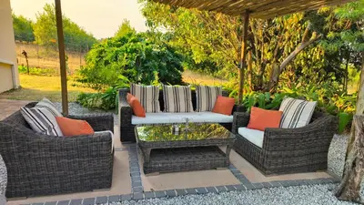 a patio with two wicker chairs and a table at Abangane Guest Lodge in Hazyview