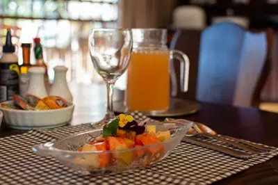 a bowl of fruit on a table with a glass of orange juice at Aberfeldy Bed & Breakfast in Midrand