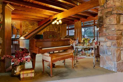 a piano in a living room with a stone wall at Aberfeldy Bed & Breakfast in Midrand