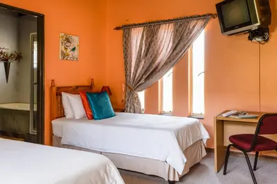 a bedroom with two beds and a desk and a television at Aberfeldy Bed & Breakfast in Midrand