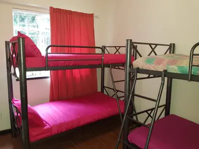 a room with two bunk beds with pink sheets at Travel Lodge Sabie in Sabie