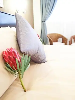 a red flower on a bed with two pillows at Travel Lodge Sabie in Sabie