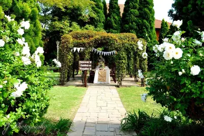 a garden with an arch with a table and white flowers at Midrand Conference Centre in Midrand