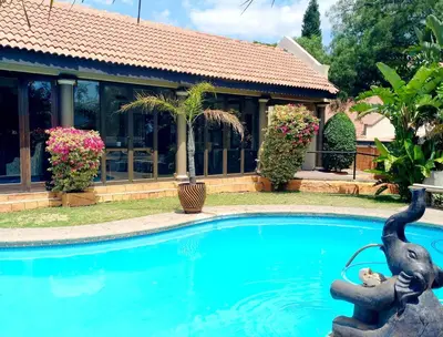 a swimming pool with a statue in front of a house at Midrand Conference Centre in Midrand