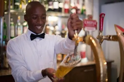 a man in a bow tie pouring a drink from a mixer at Premier Hotel The Winkler in White River