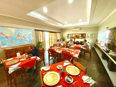 a group of people sitting at tables in a restaurant at Amper Bo Guest House in Pretoria