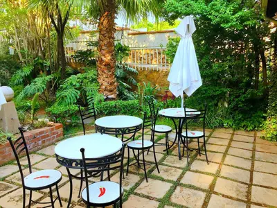a group of tables and chairs with an umbrella at Amper Bo Guest House in Pretoria