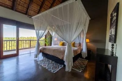 a bedroom with a canopy bed and a balcony at Parsons House in Hoedspruit