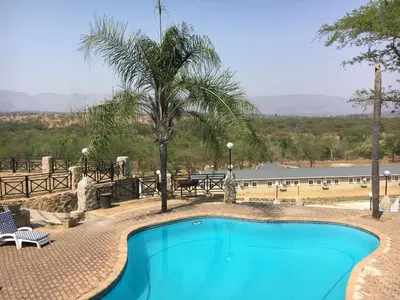 a swimming pool with a palm tree and a building at African Rest Lodge in Barberton