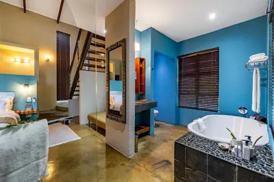 a bathroom with blue walls and a tub and a bedroom at Francolin Lodge in Nelspruit