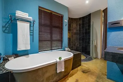 a blue bathroom with a tub and a sink at Francolin Lodge in Nelspruit