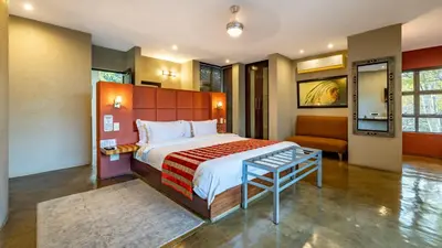 a bedroom with a large bed and a chair at Francolin Lodge in Nelspruit