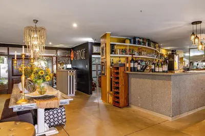 a bar in a restaurant with a vase of flowers on a table at Francolin Lodge in Nelspruit