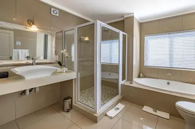 a bathroom with a shower and a sink and a tub at Loerie's Call Guesthouse in Nelspruit
