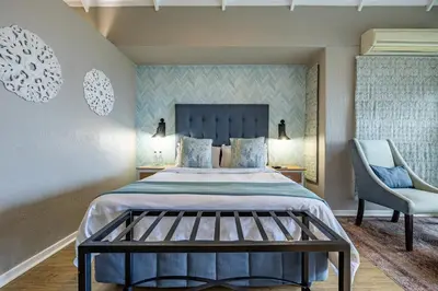 a bedroom with a large bed and a chair at Loerie's Call Guesthouse in Nelspruit