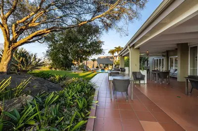 a patio with tables and chairs on a house at Loerie's Call Guesthouse in Nelspruit