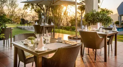 a patio with tables and chairs and an umbrella at Loerie's Call Guesthouse in Nelspruit