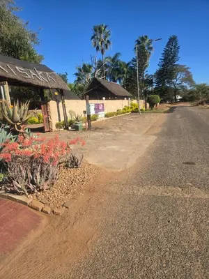 an empty road next to a building with flowering plants at Xisaka Guest House in Giyani
