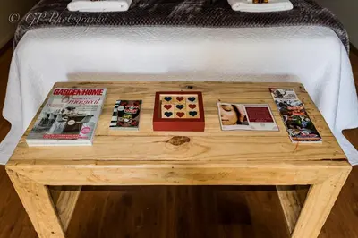 a wooden table with magazines on top of a bed at Laguna Lodge in Graskop