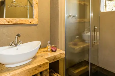 a bathroom with a sink and a glass shower at Laguna Lodge in Graskop