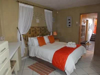 a bedroom with a bed with orange and white pillows at Tatenda Guest House in Hazyview