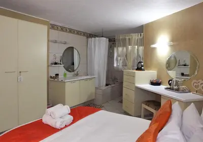 a bedroom with a bed and a bathroom with a sink at Tatenda Guest House in Hazyview