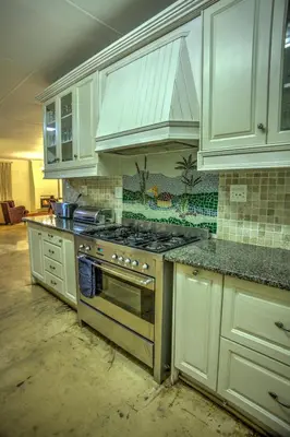 a kitchen with a stove and white cabinets at Pavetta Country House in Magoebaskloof