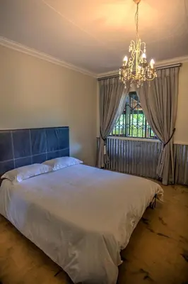 a bedroom with a large bed and a chandelier at Pavetta Country House in Magoebaskloof