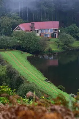a house on a hill next to a body of water at Pavetta Country House in Magoebaskloof