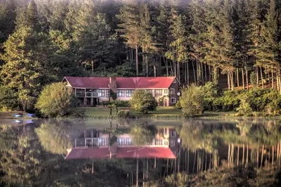 a house on the shore of a lake at Pavetta Country House in Magoebaskloof